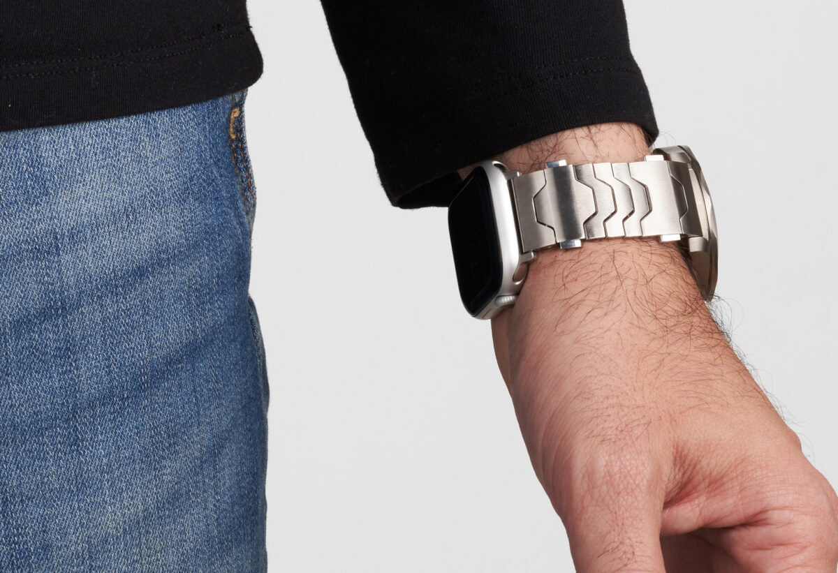 Ein Mann, der am Tisch sowohl eine Rolex als auch eine Apple Watch trägt